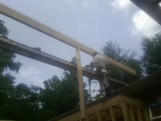 Carpenter setting a ridge beam over a new addition frame — Ice Dam Removal by Roofing Brothers in Hutto