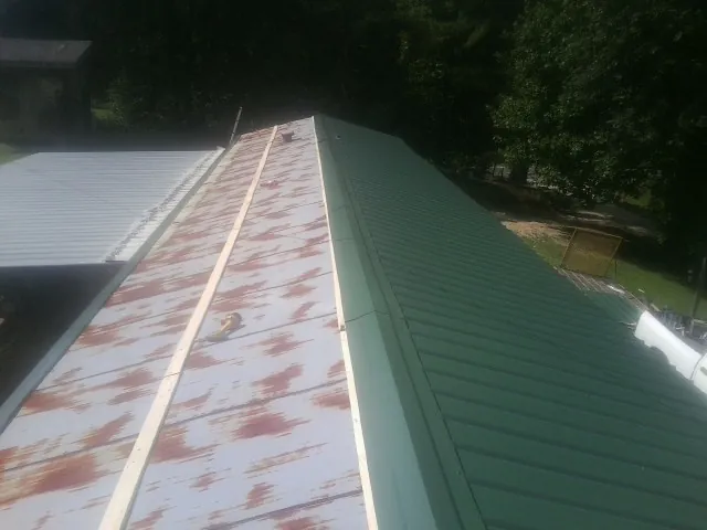 Old rusted panels beside newly installed green metal roofing — Wind Damage Roof Repair by Roofing Brothers in Hutto