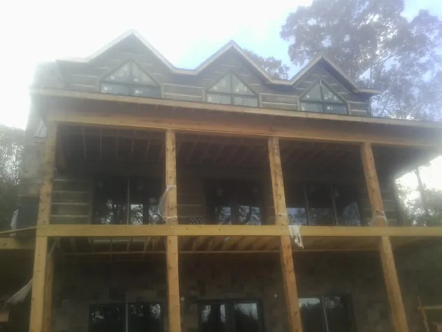 Dormers and porch framing on a large log home under construction — Roof Coating work by our crew in Hutto