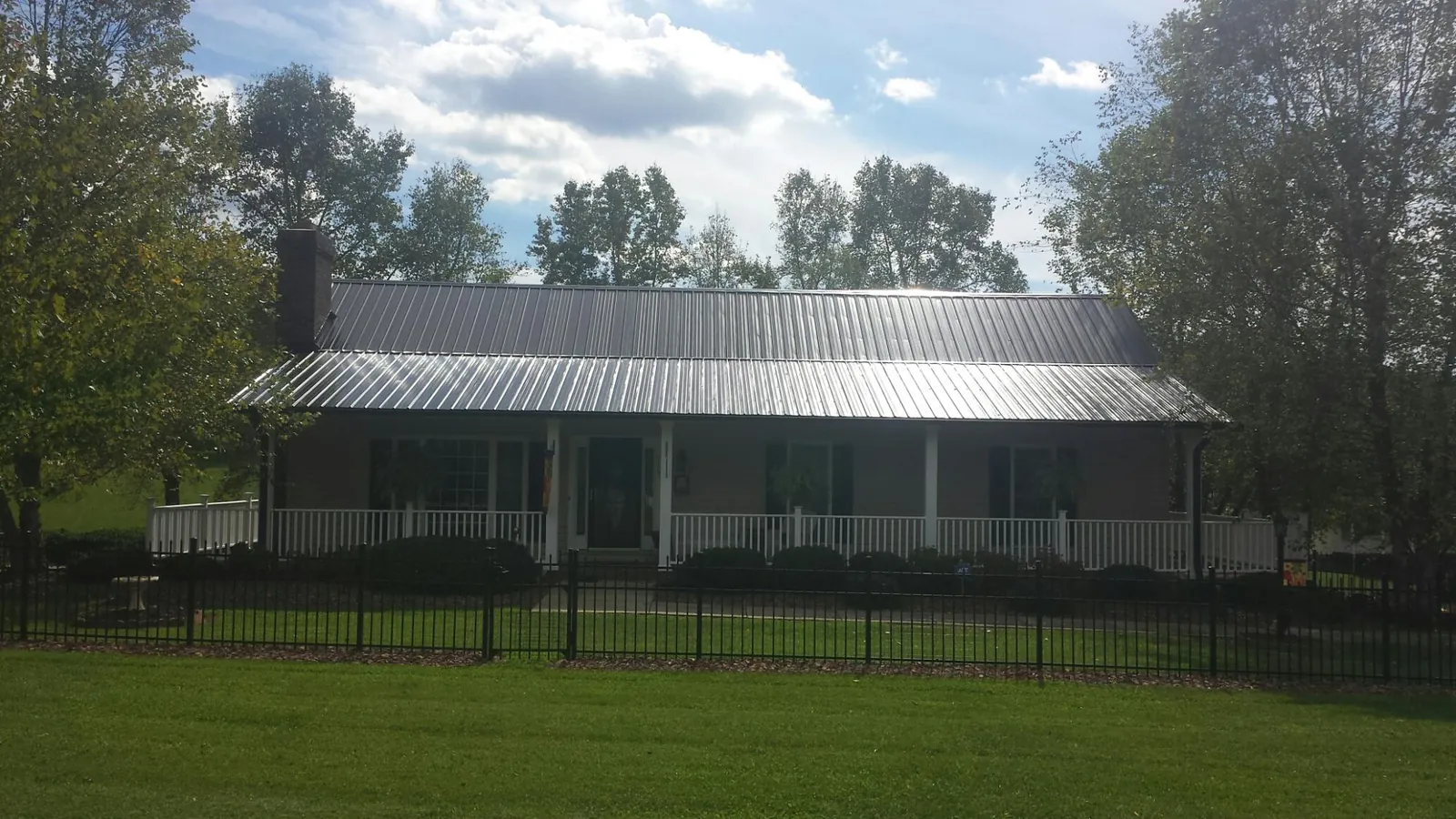 Gray metal roof on a brick ranch with a full width front porch — Gutter Guard Installation work by our crew in Hutto
