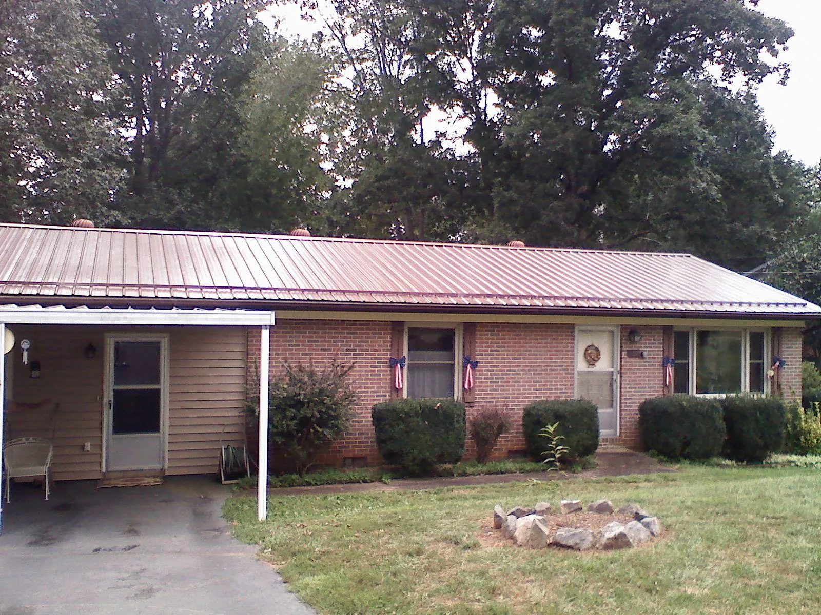 Bronze metal roof and carport on a brick ranch home — Roof Repair work by our crew in Hutto